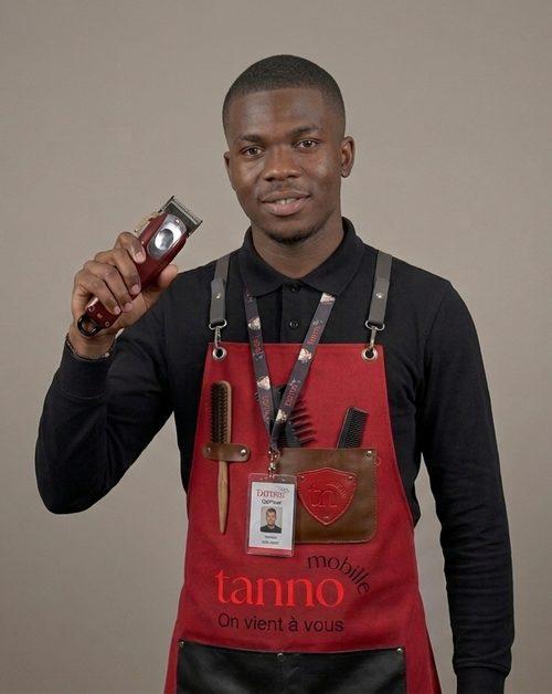 Coiffeur Tanno en tablier, sa tondeuse à la main